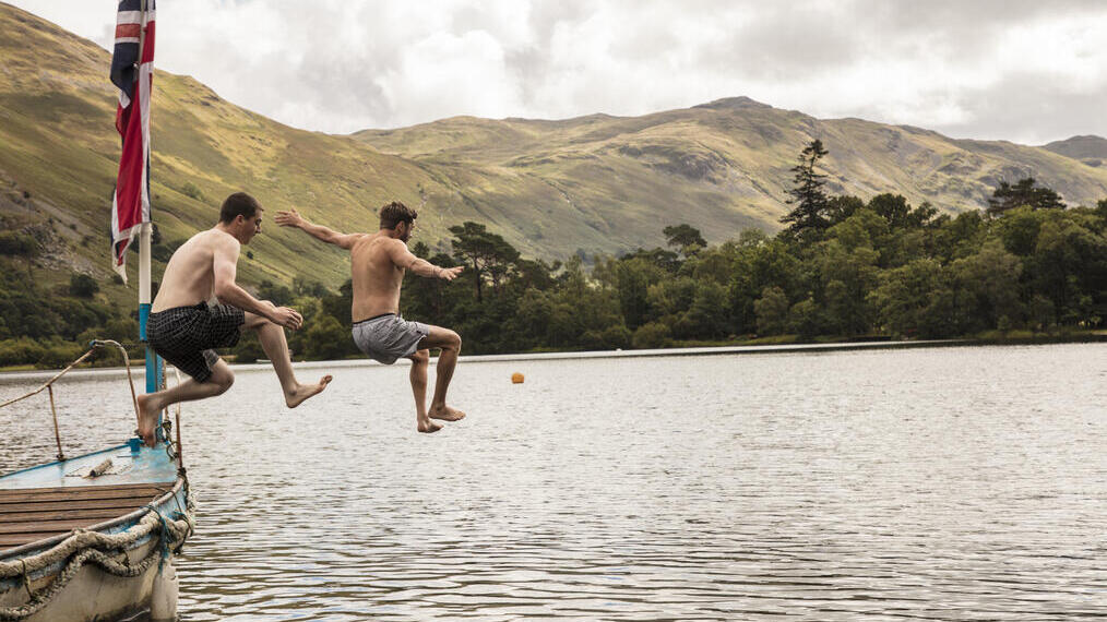 Two men jumping off a boat into the lake