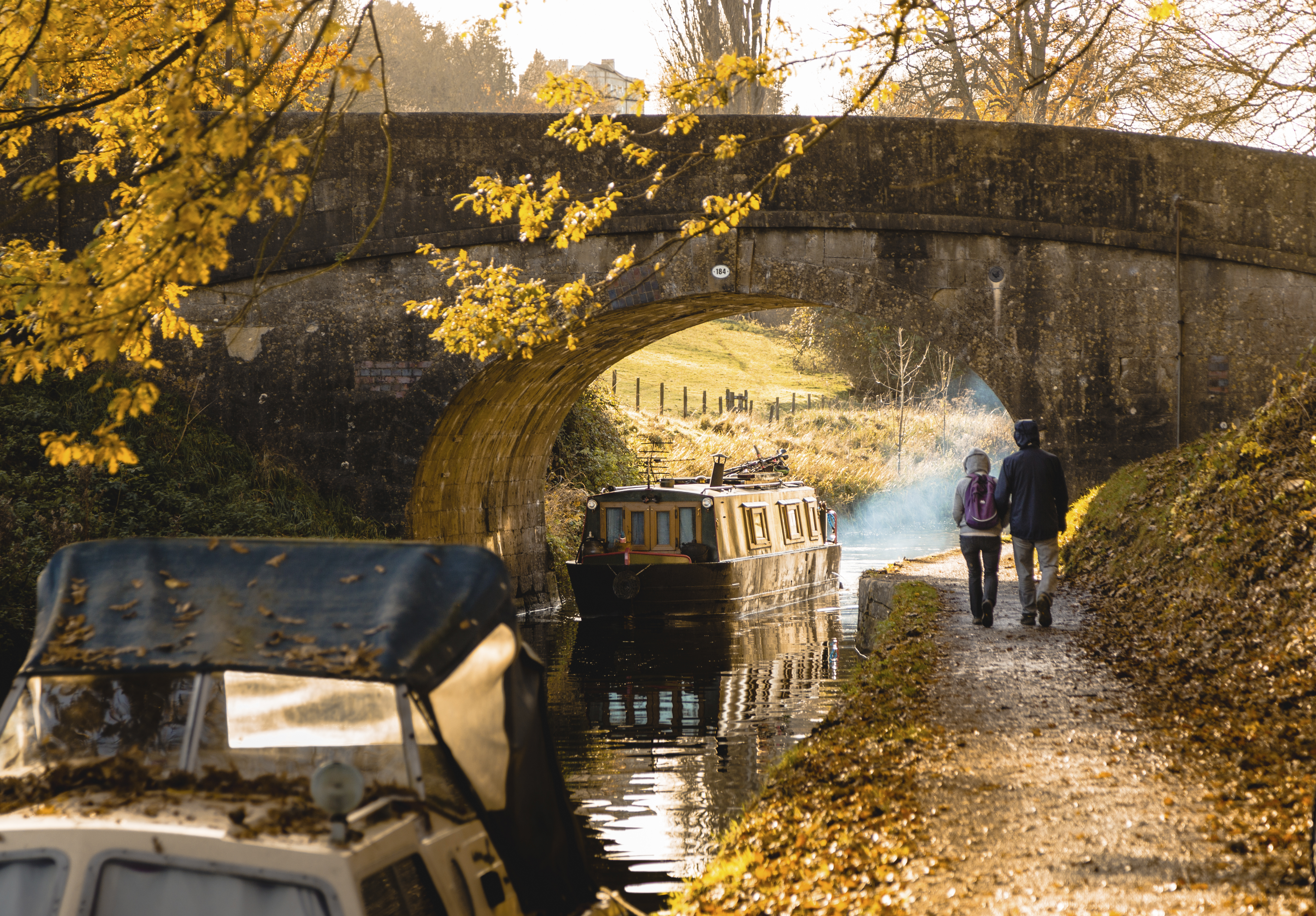 Man and woman walking beside a canal near a low bridge
