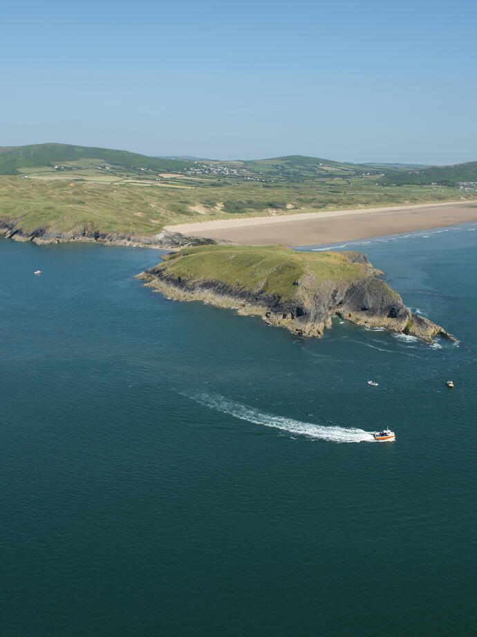 Un hors-bord en mer suit la côte dans des eaux d'un bleu profond