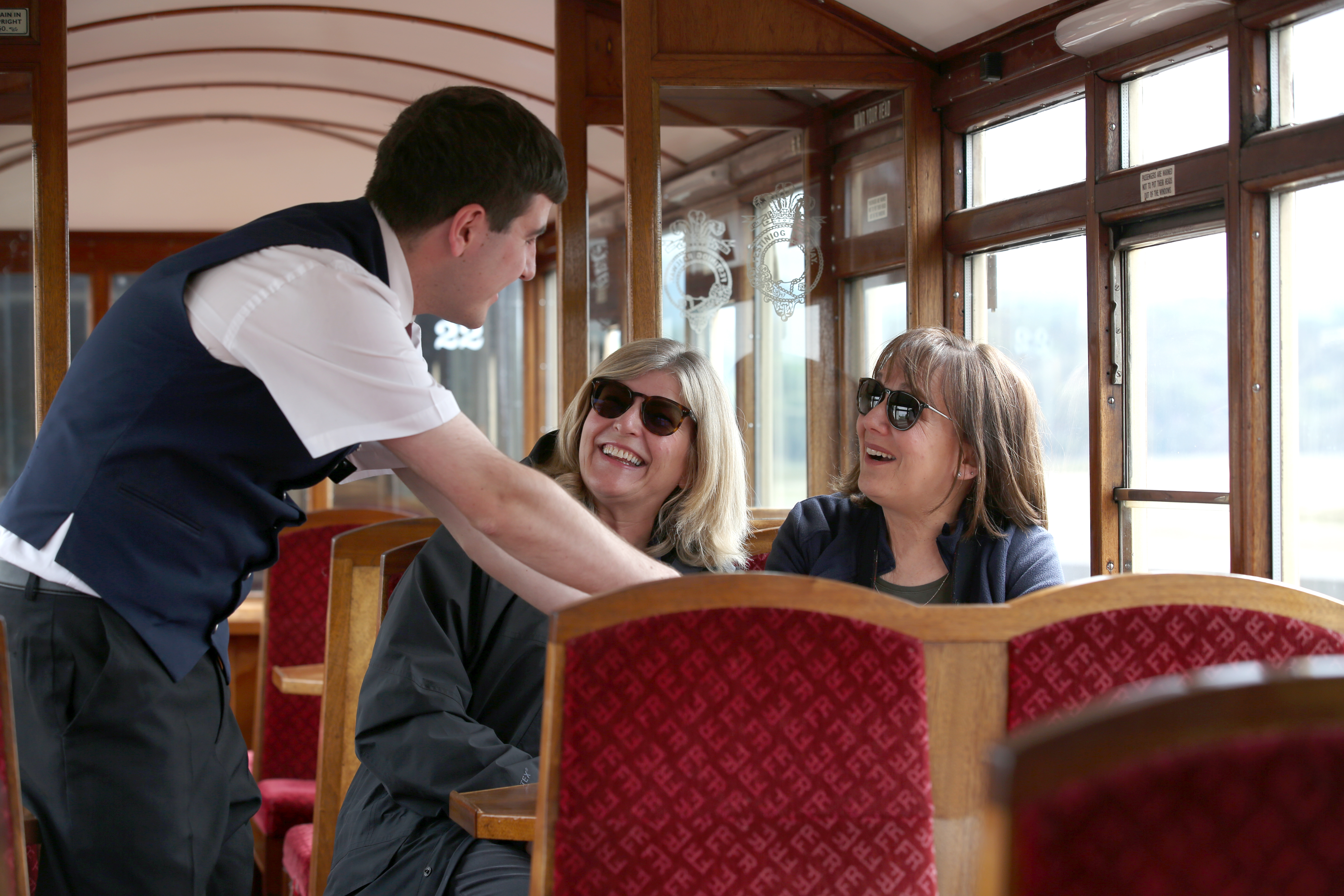 Railway passengers on a heritage train talking to crew member.