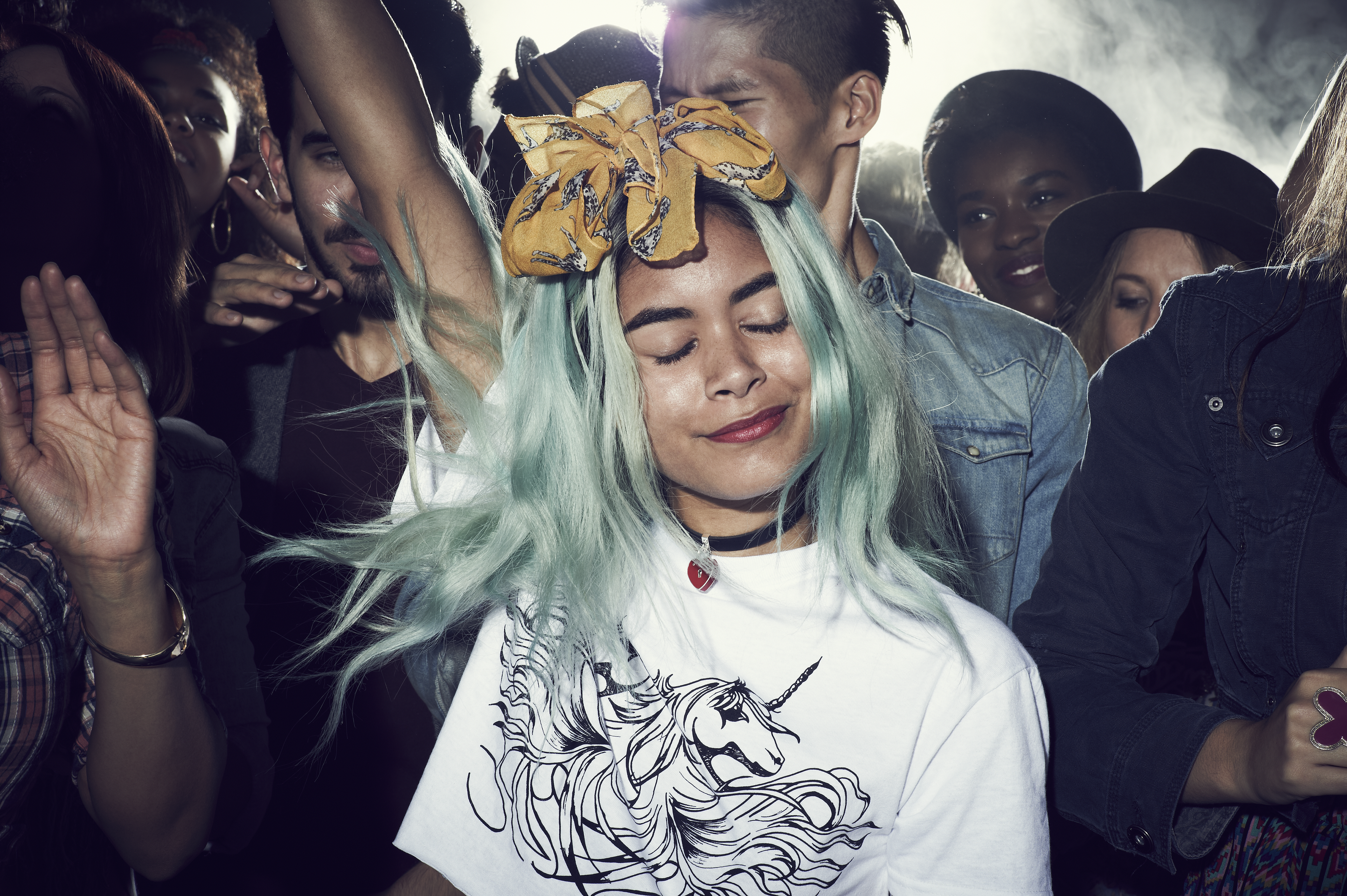 Girl with dyed hair, smiling, dancing with a group of people