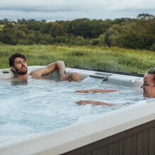 Couple relaxing in a hot tub overlooking countryside