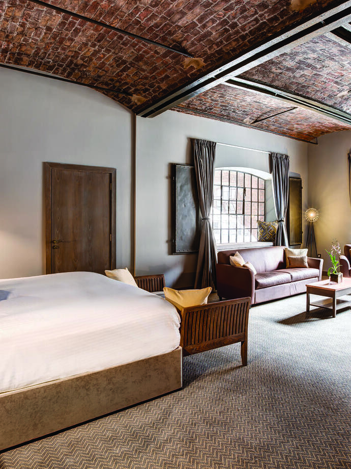 Une grande chambre double avec un plafond voûté en briques et deux fenêtres.