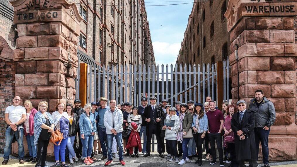 Un groupe de touristes participant à la visite guidée Peaky Blinders posant devant un entrepôt industriel à Liverpool