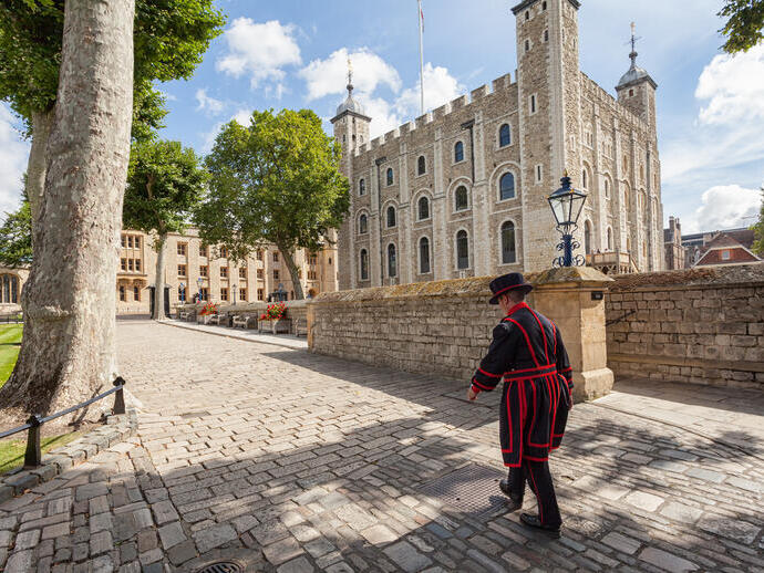 Beefeater walking by the Tower of London on a sunny day