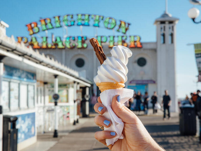 Close up of person holding ice cream cone on pier