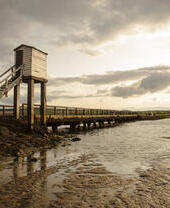 Two people by an elevated causeway at low tide