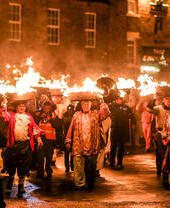 A procession of people in costumes with flaming containers on their heads - Allendale Tar Bar’l
