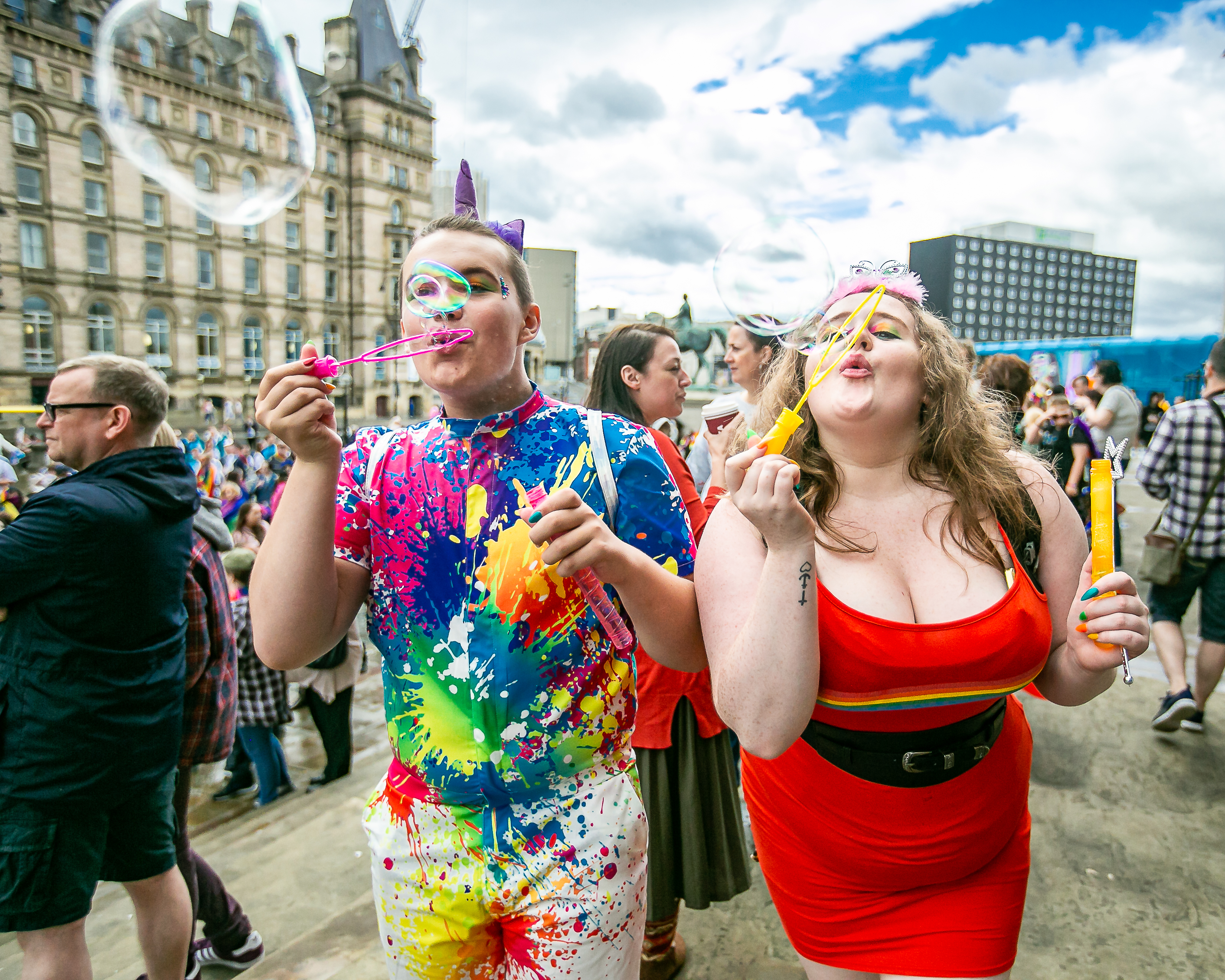 Two people celebrating Liverpool Pride by blowing bubbles towards the camera