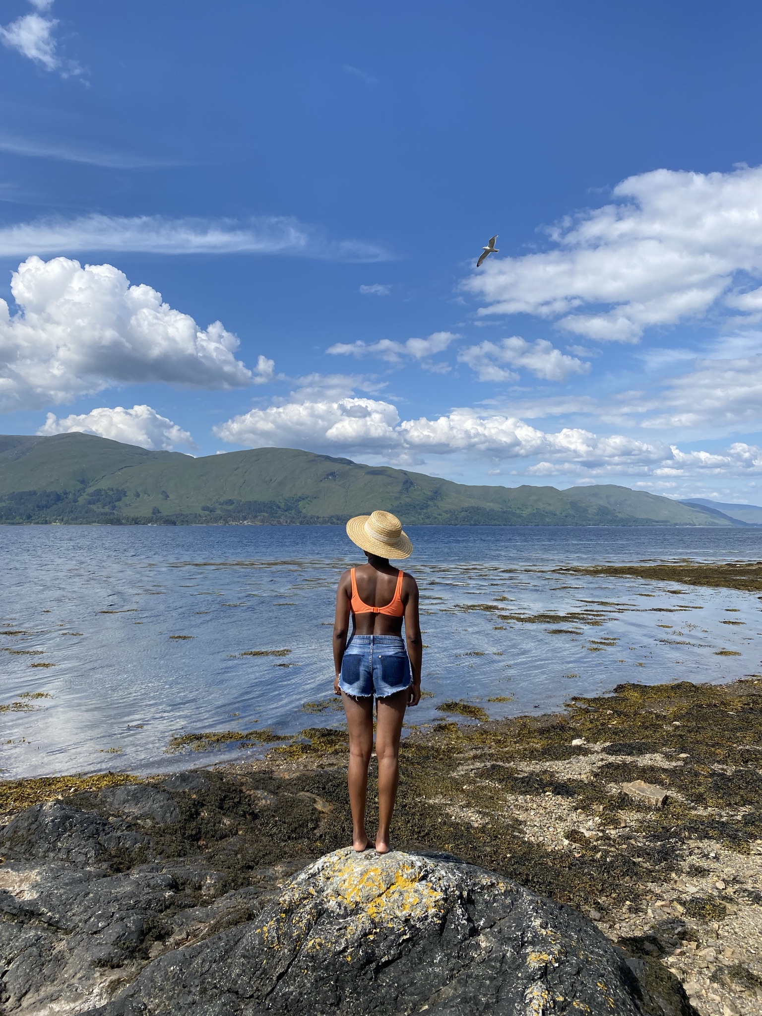 Woman stands on a rock looking over a lake