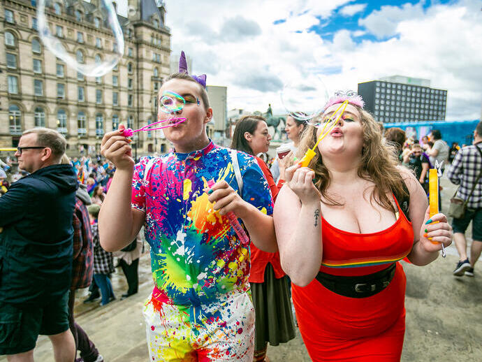 Zwei Personen feiern den Liverpool Pride, indem sie Seifenblasen in Richtung Kamera pusten