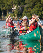 Famiglia con bambini che fa canoa su un fiume