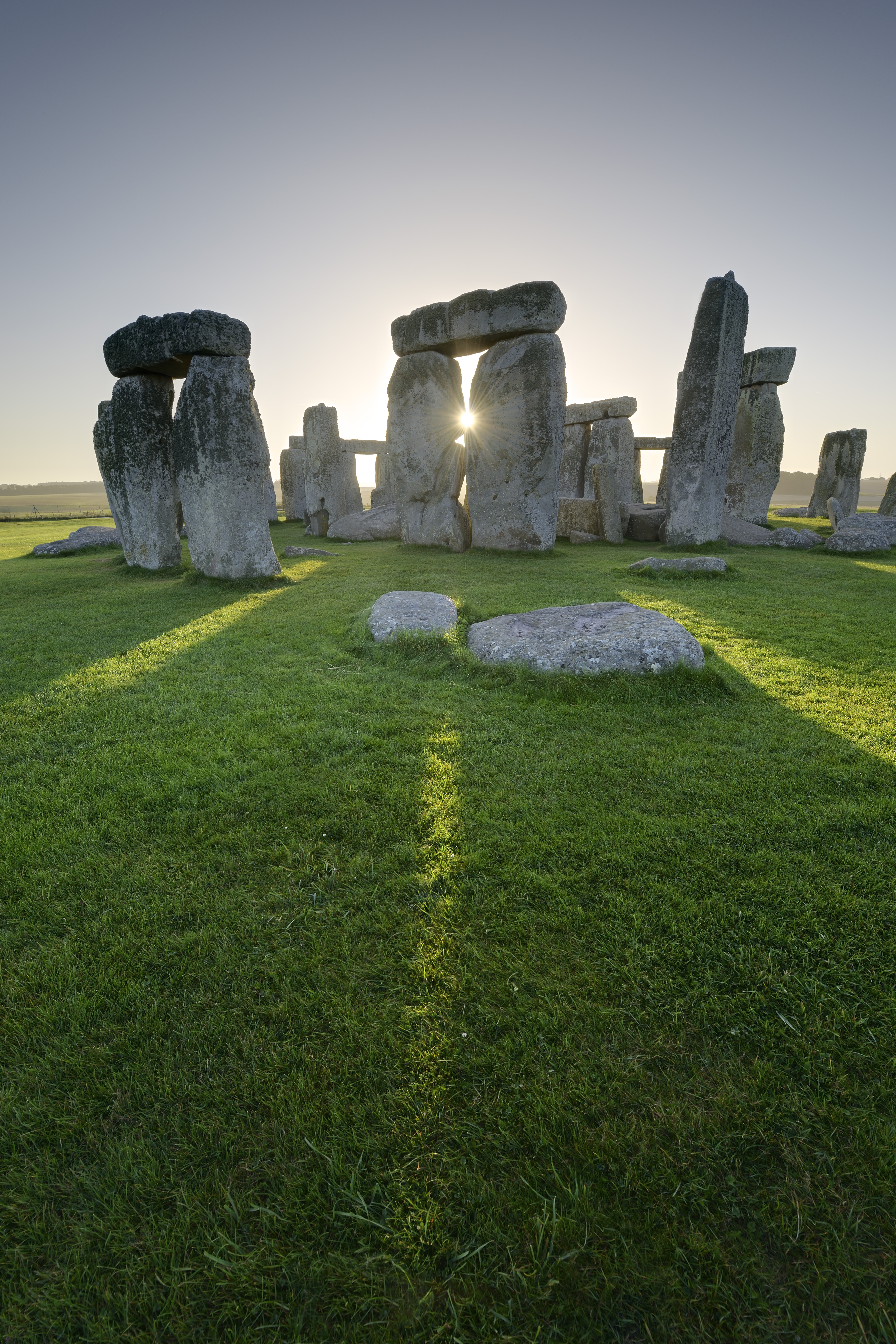 Large stone pillars arranged in circle on grass. Sunset