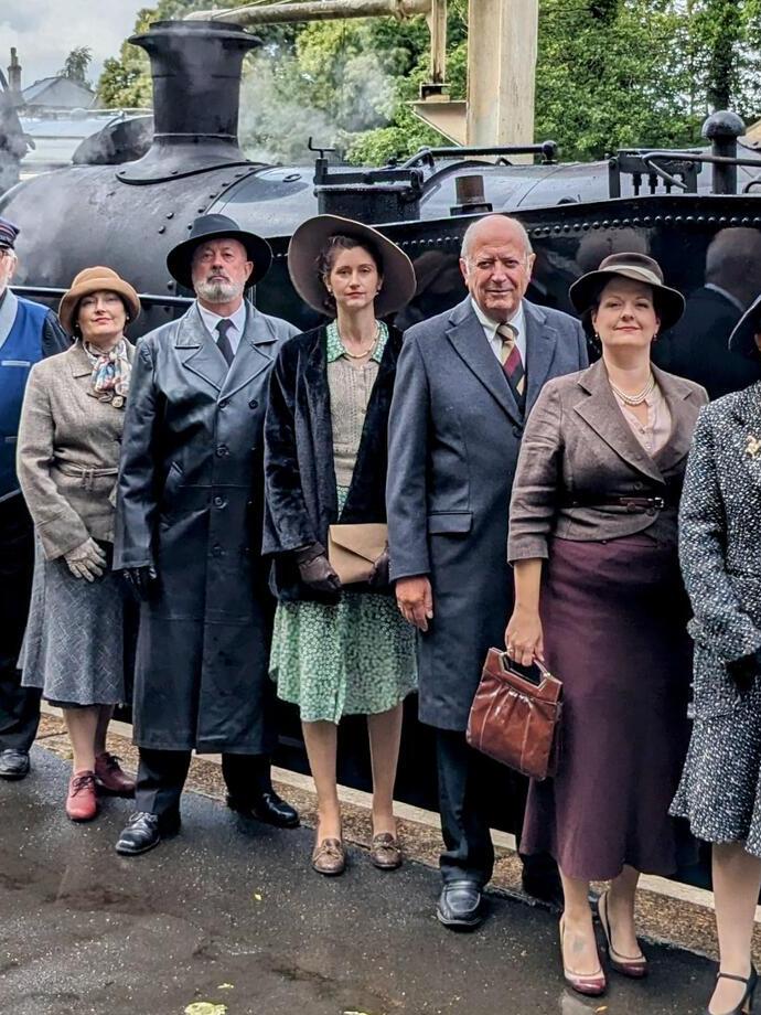 Actors in costume in front of a steam train as part of a murder mystery performance