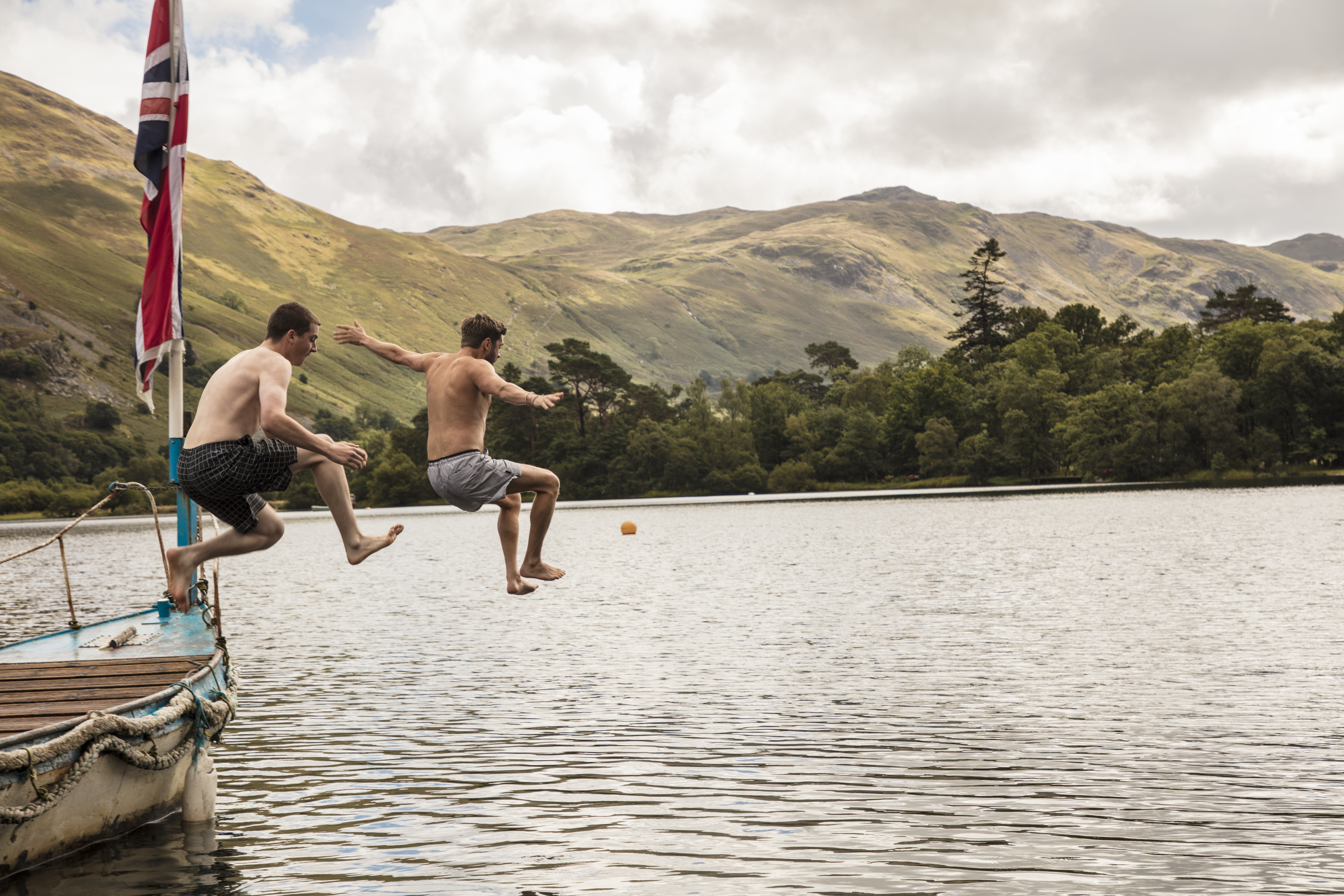 Two men jumping off a boat into the lake