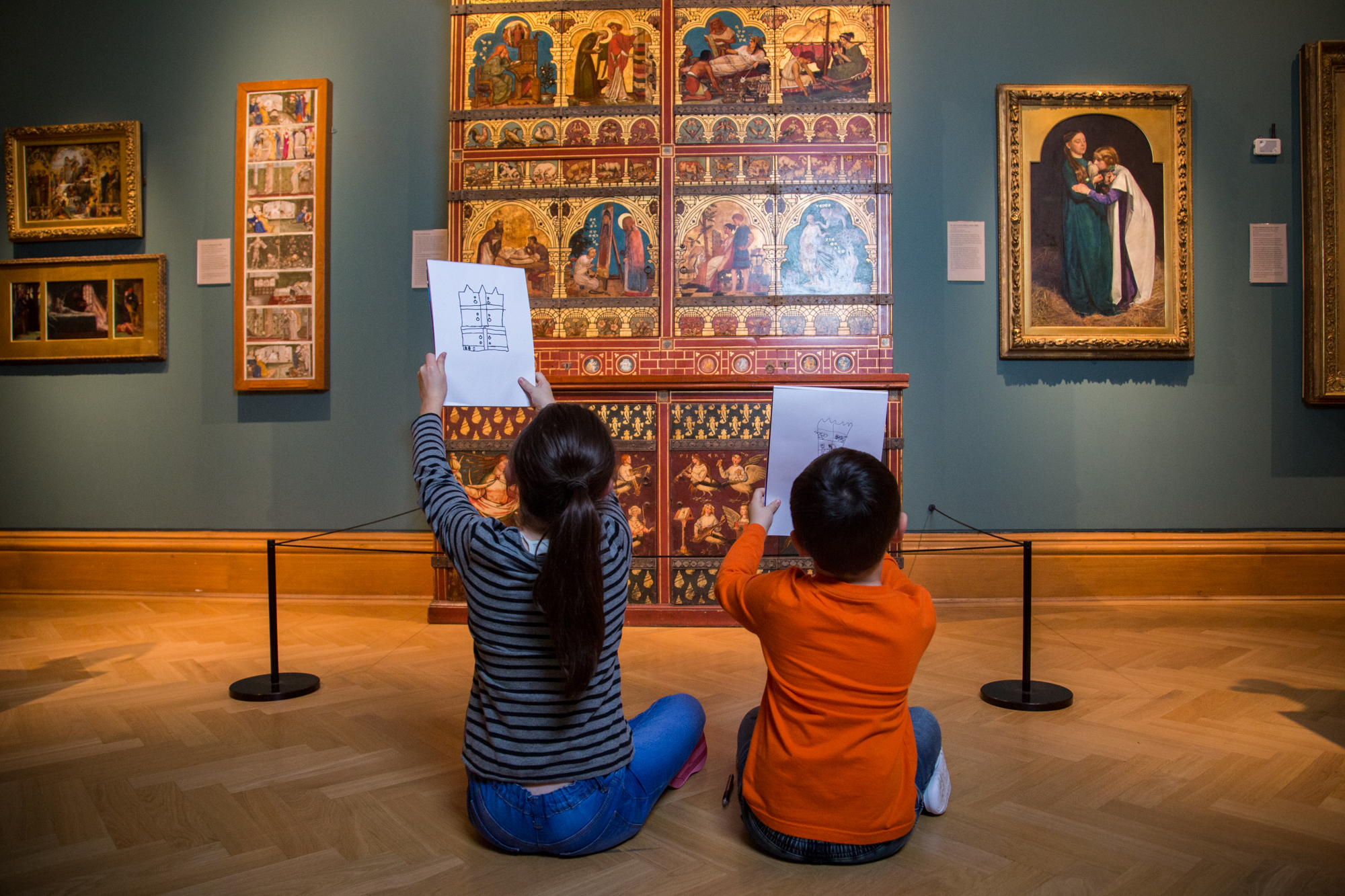 Two children seated on floor drawing museum exhibits