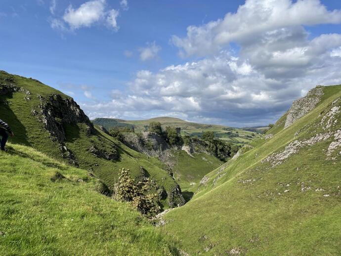 Viewing point from the end of a valley, looking down below with grass in the foreground.
