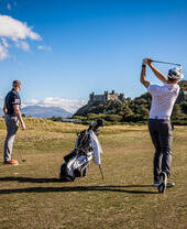 A pair of golfers teeing off at Royal St David's Golf Club in Wales