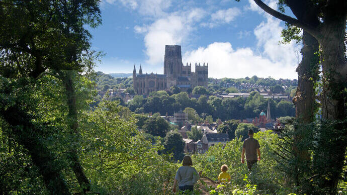 Family walking on a hill top looking down on to Durham Cathedral