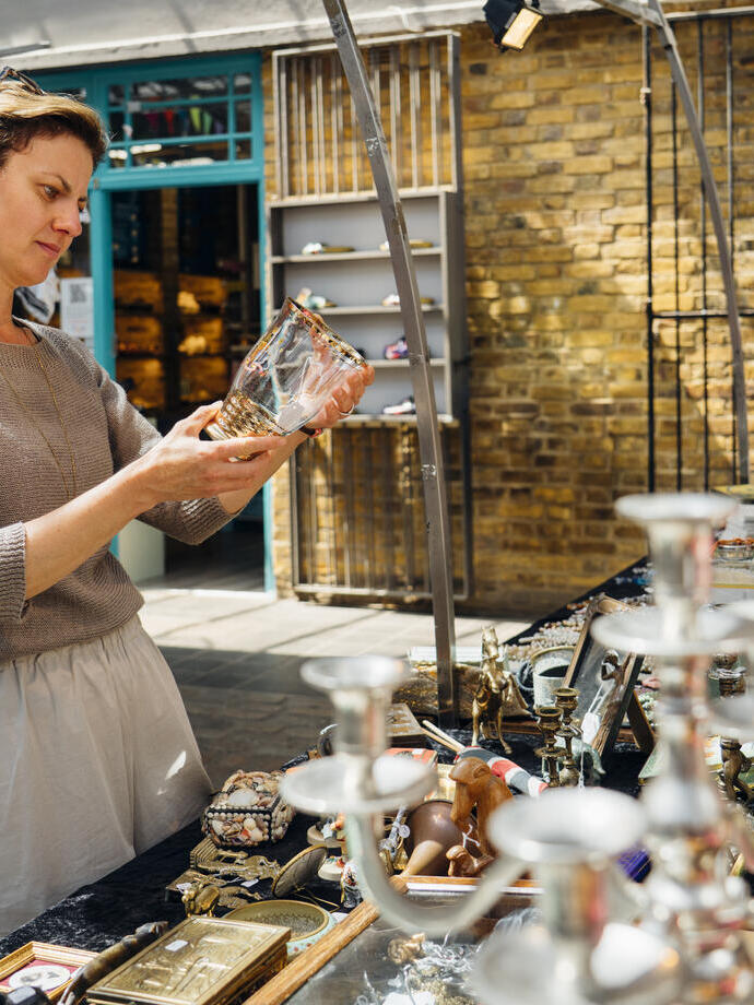 Frau begutachtet einen Glasgegenstand auf einem Flohmarkt