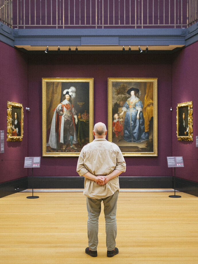 Rear view of man standing looking at portraits in a gallery