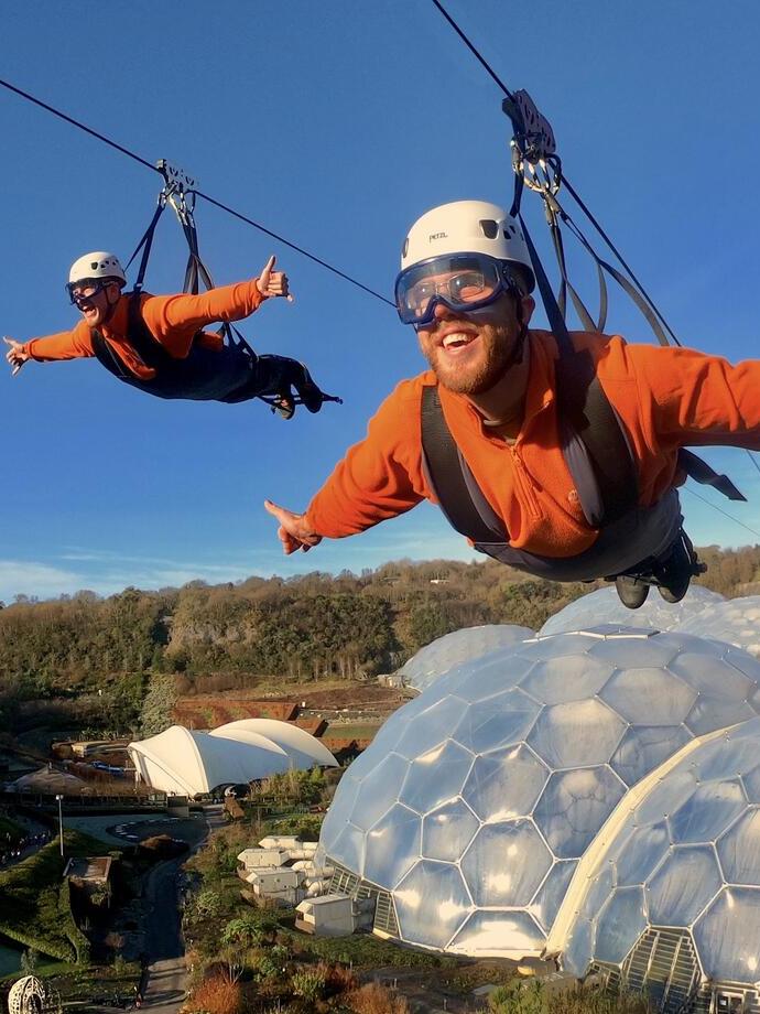 Two people suspended on a zipline above the Eden Project