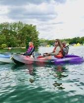 Three people in kayaks in a lake at the New Forest Water Park