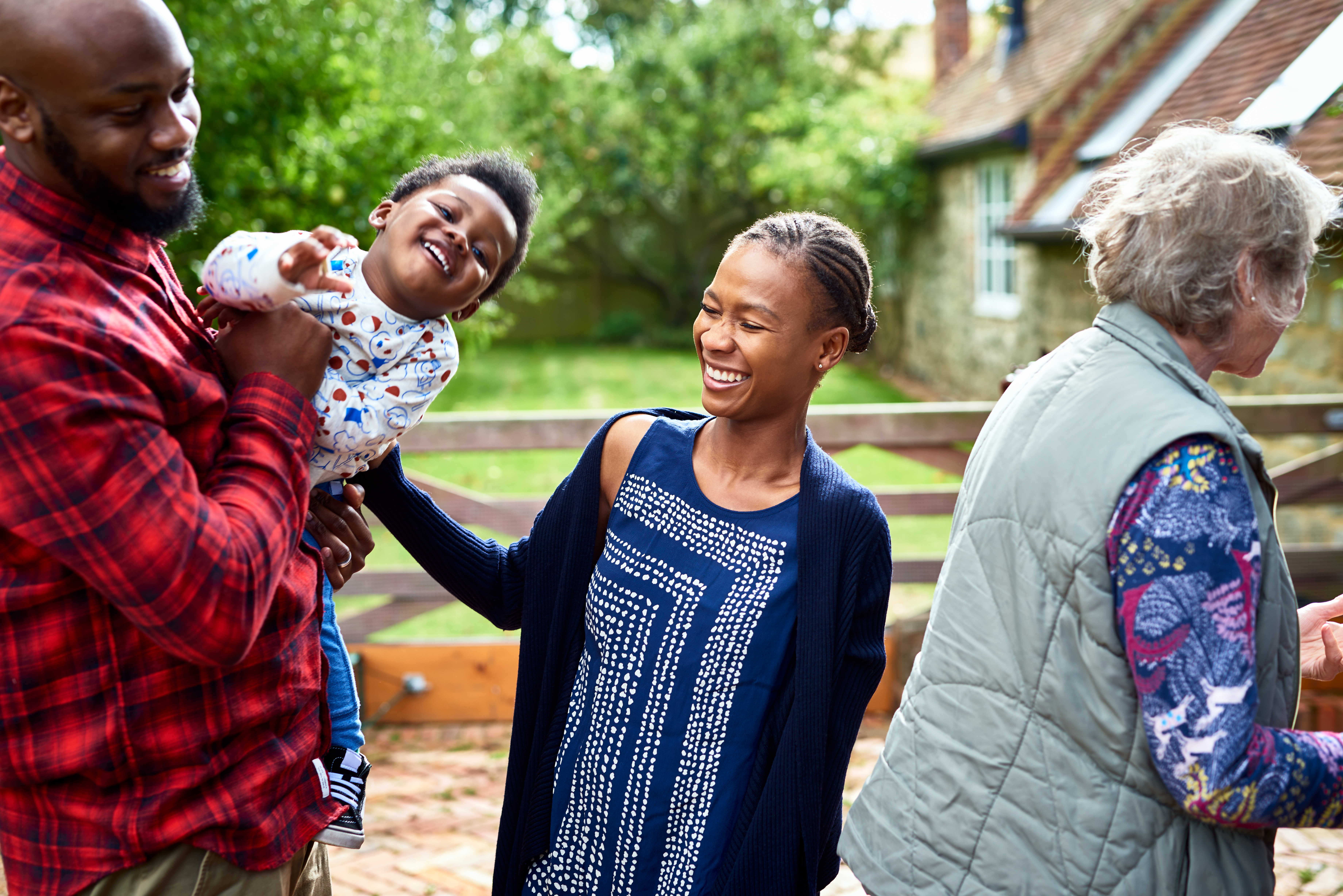 Family laughing in rural setting by a house
