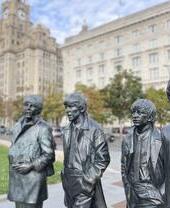 Statue of four men with a large building and clocktower in the background