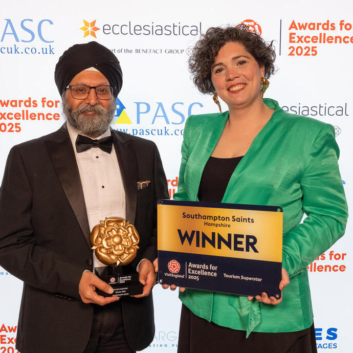 Two winners smiling and posing with their plaque on stage at a gala ceremony.