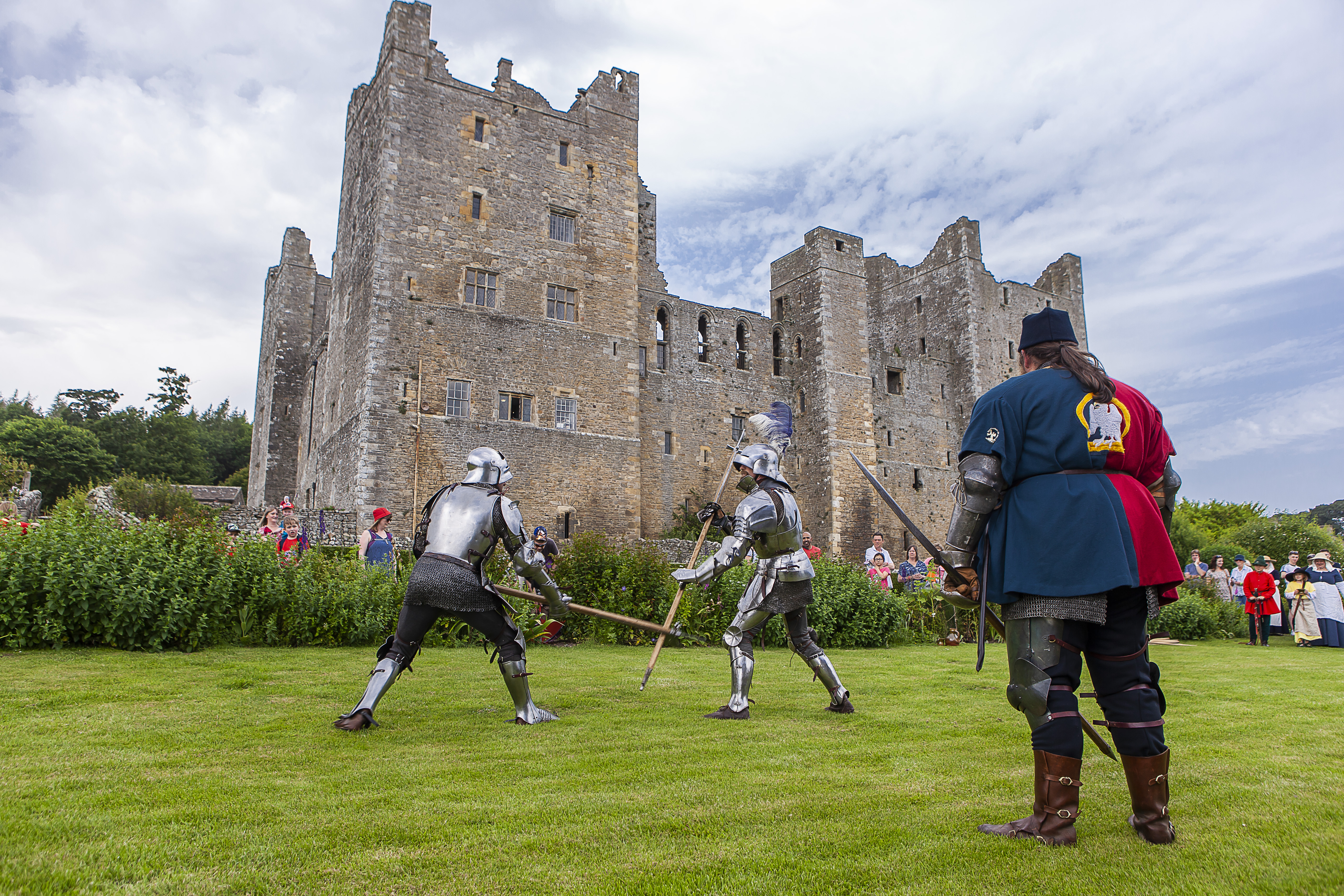 Two men in full knight armor putting on a performance for a watching crowd at Bolton Castle, Yorkshire