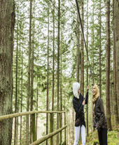 Two women preparing to go on a zipwire in the pine forest