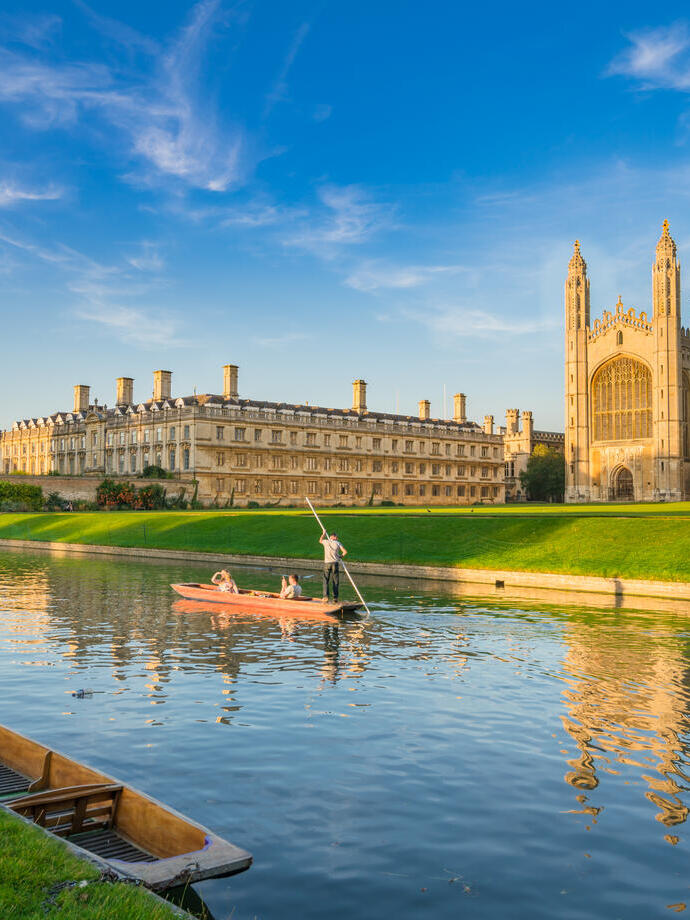 People punting along a river next to a college and chapel.