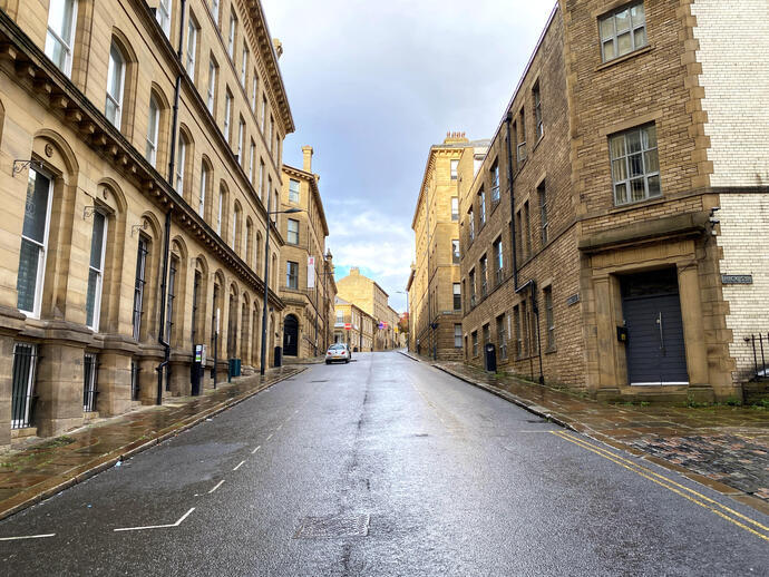 Looking up a deserted road, lined with Victorian stone buildings