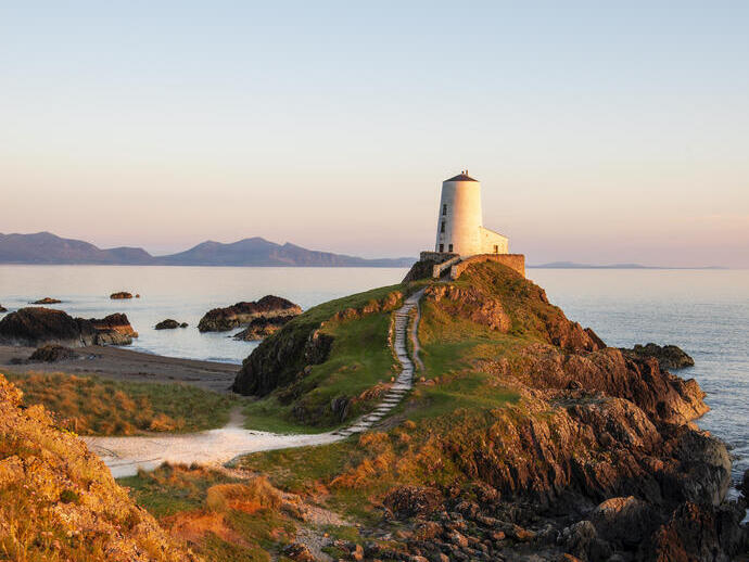 Ein Weg, der zu einem Leuchtturm auf einem markanten Felsvorsprung am Meer führt