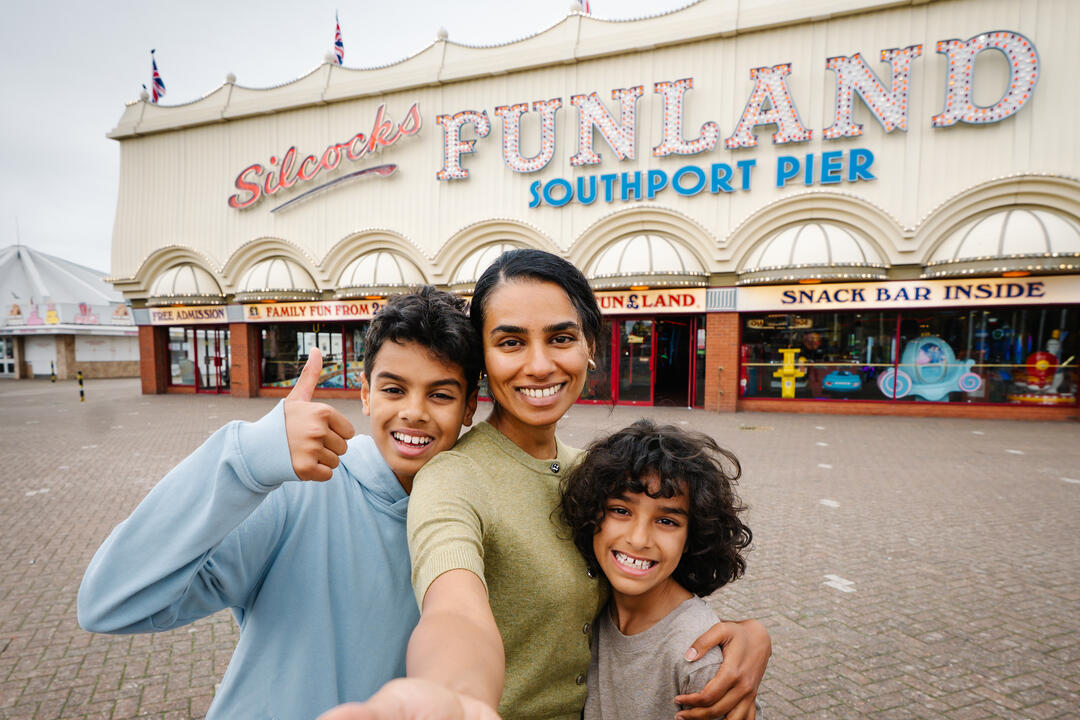 A mother and two sons stand outside an amusement park