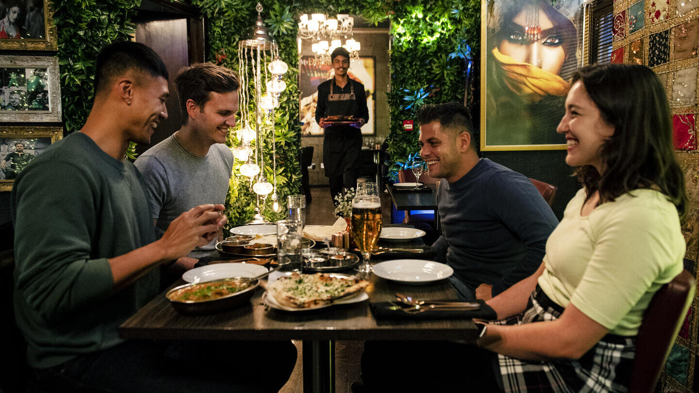 Friends sitting in an Indian restaurant eating food