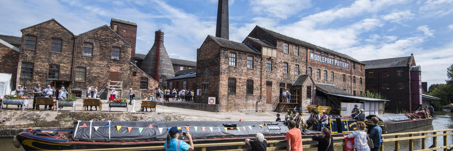 A group of people looking across the Trent and Mersey Canal at several historic buildings in Stoke