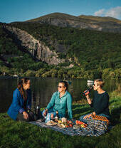 Amici che fanno un picnic in un prato vicino a un lago di origine glaciale.