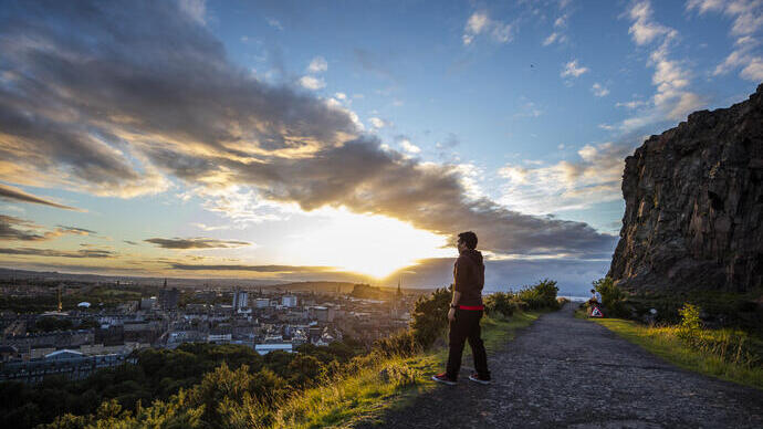 Man enjoying panoramic views of Edinburgh at the top of Arthur's Seat
