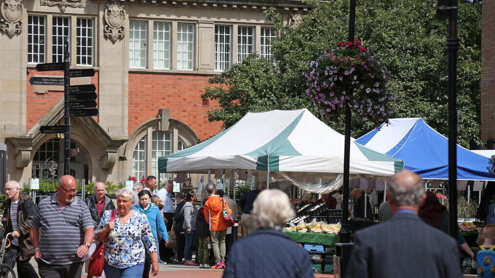 People visiting an outoor produce market near a historic building.