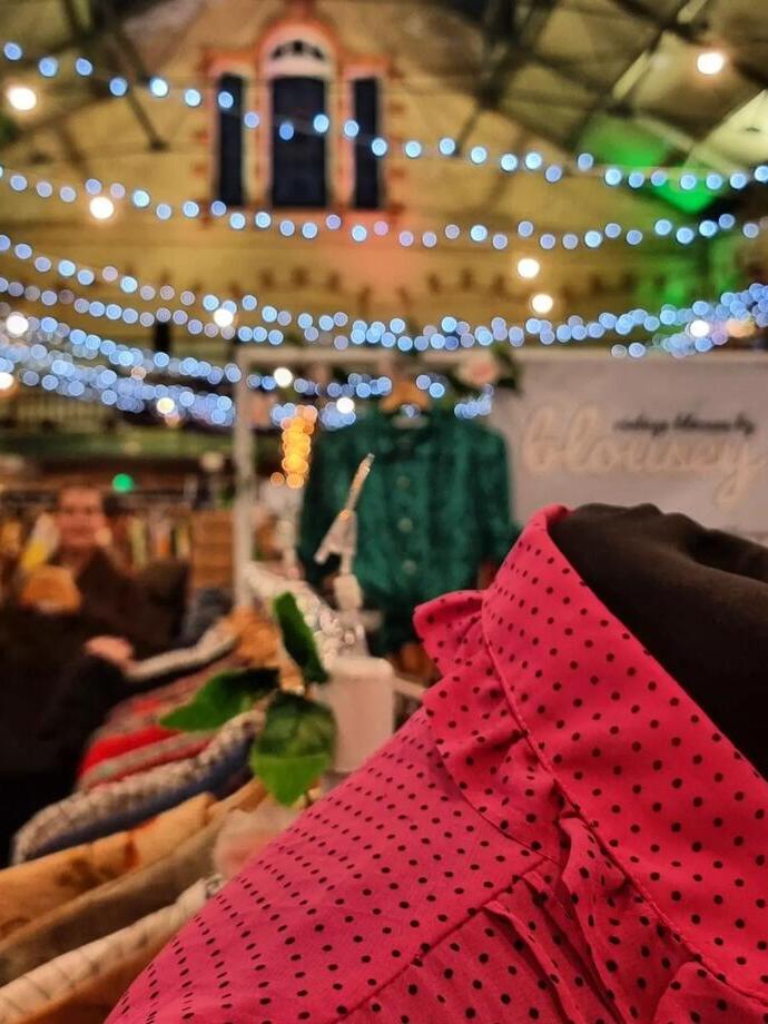 Primo piano di abiti su una bancarella al mercato di Victoria Baths con luci colorate sullo sfondo
