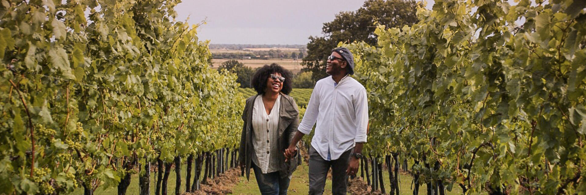 Un homme et une femme marchant entre les rangées de vignes dans un vignoble