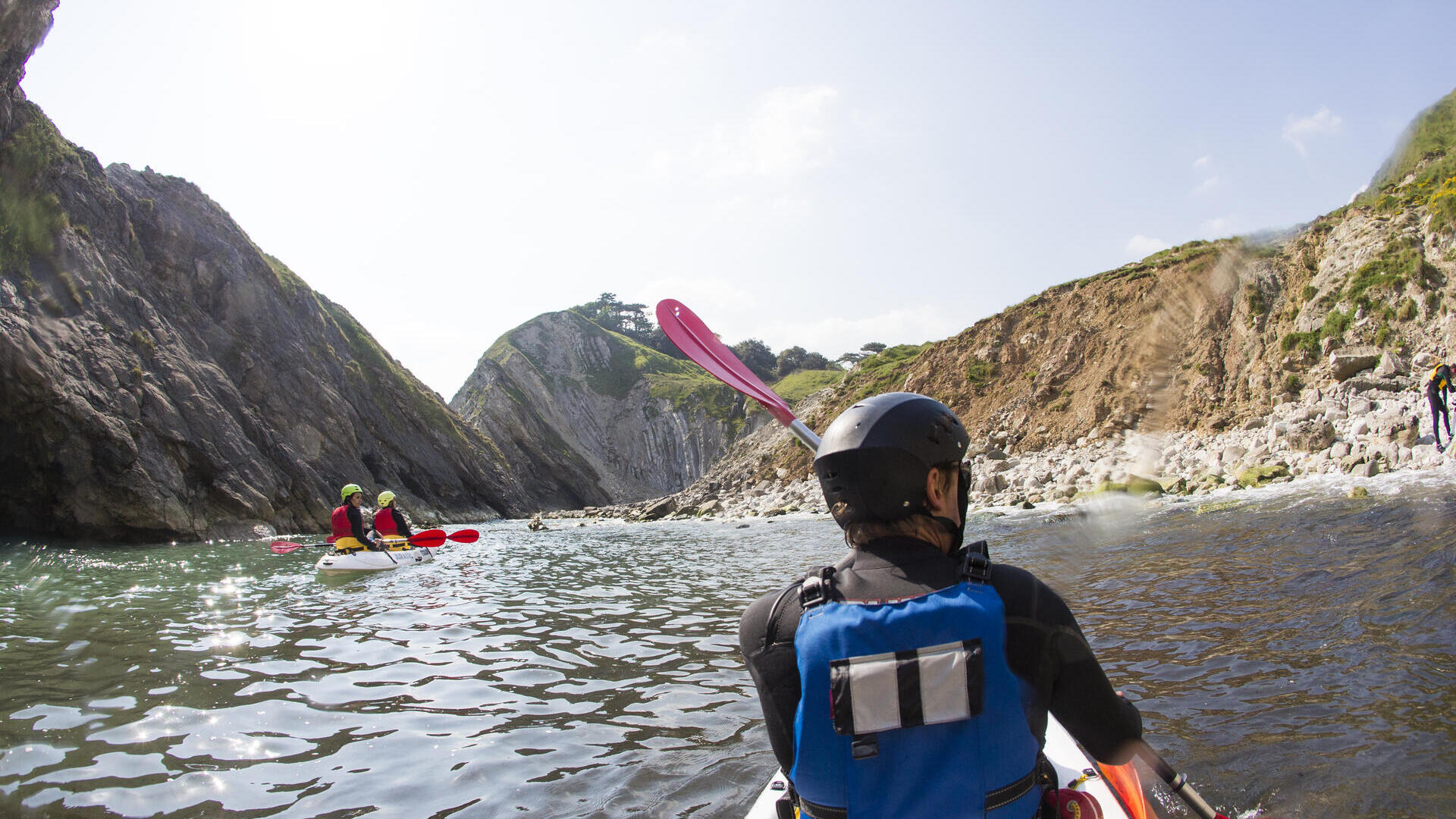 People kayaking along the shores of coastline