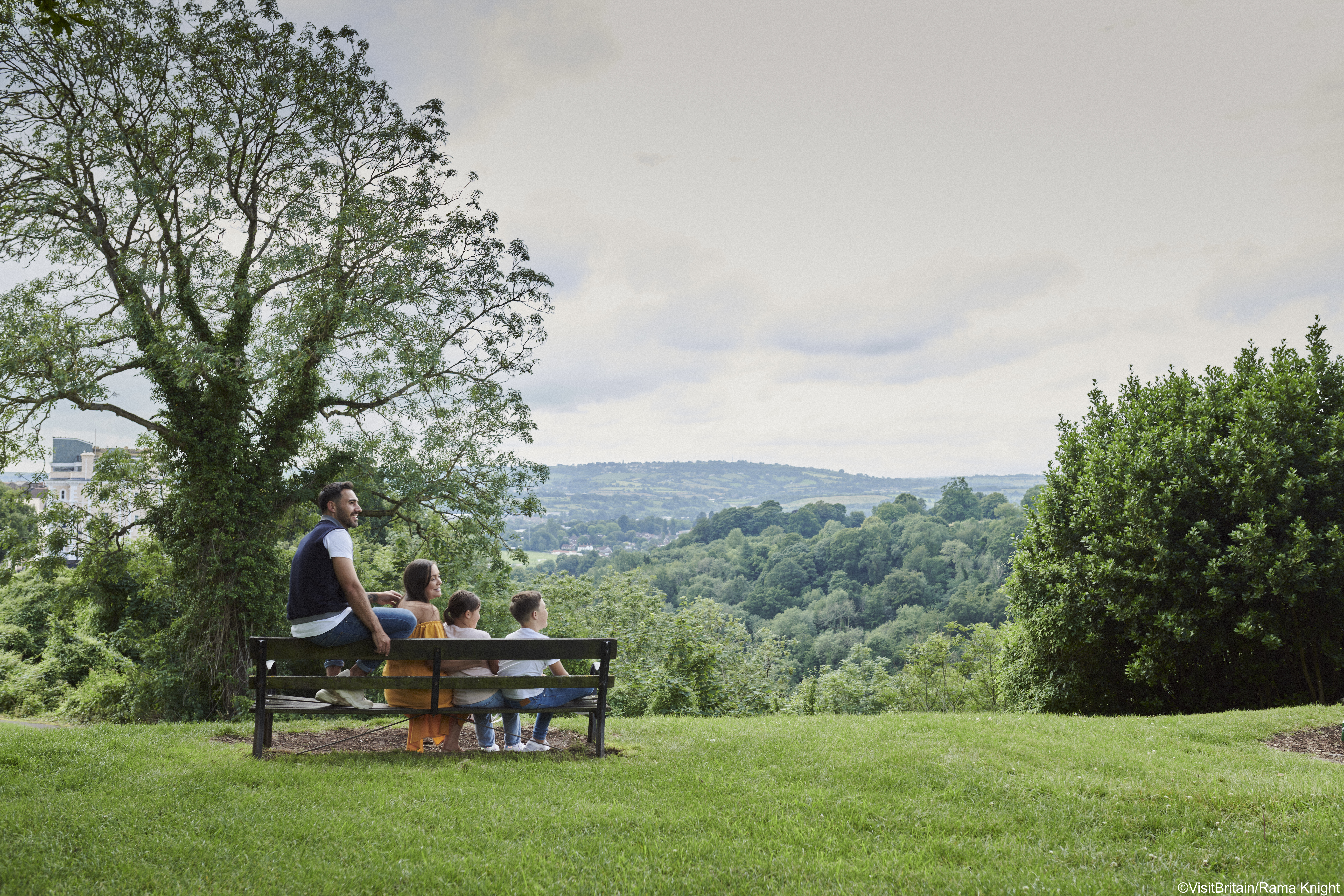 Family sit on a bench in park during summer