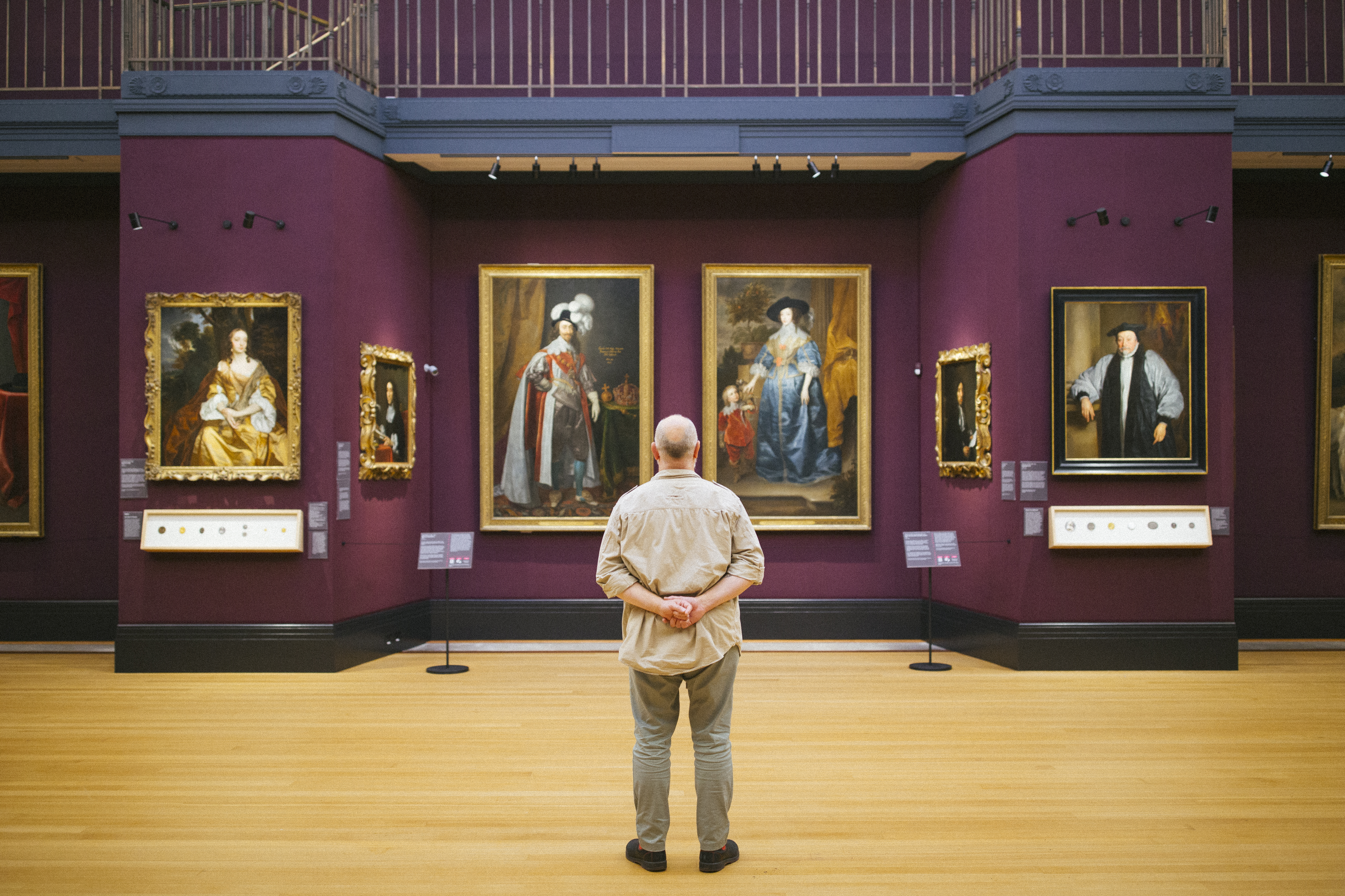 Rear view of man standing looking at portraits in a gallery