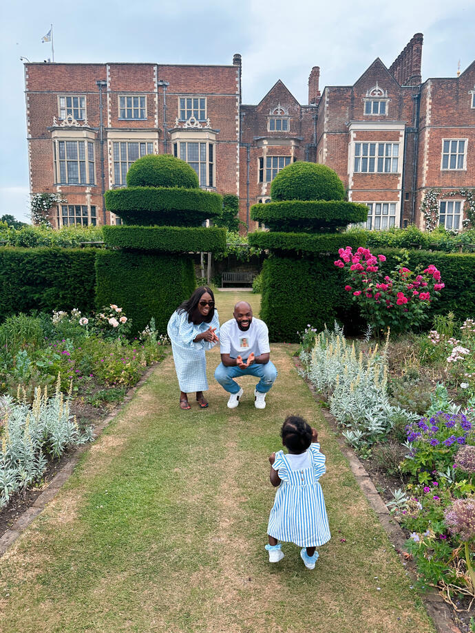Man, woman and child playing in formal garden of large country house