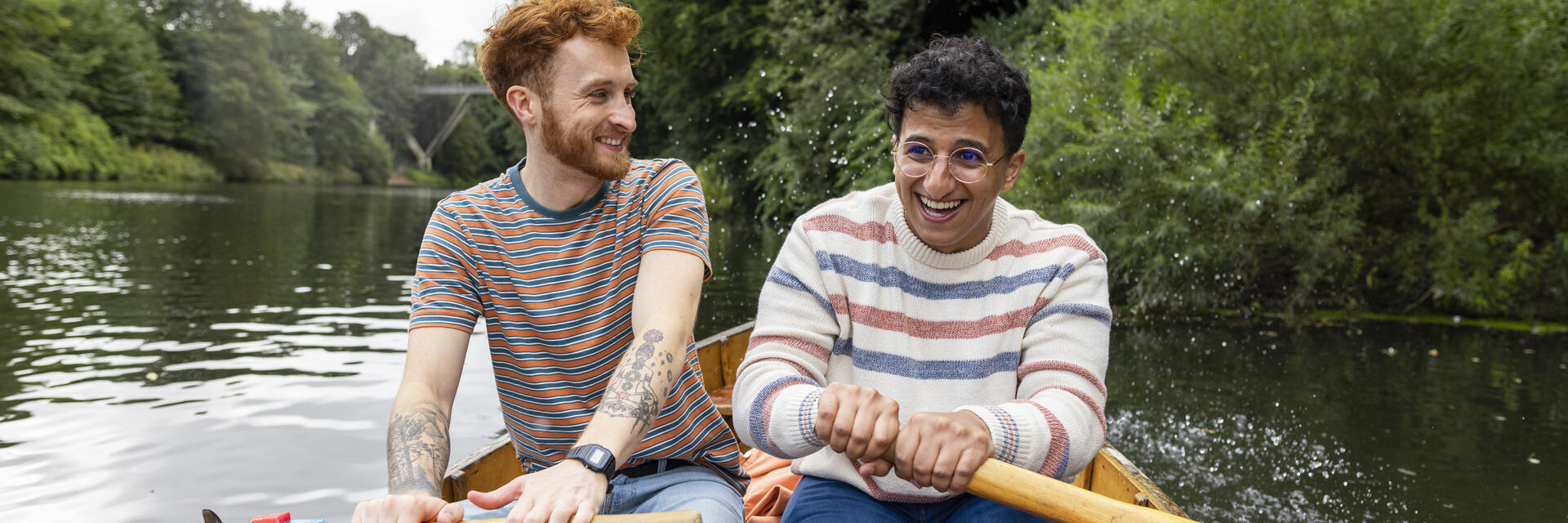 A male couple sitting in a rowboat, rowing together