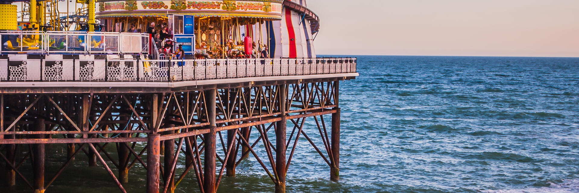 A fun fair on the end of a pier with a jet ski in the sea below