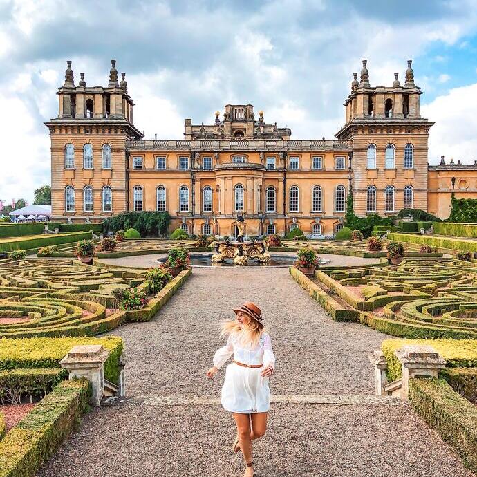 Femme marchant dans les jardins à la française devant un palais